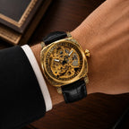 Gold mechanical watch with black leather strap on a wrist, close-up shot.